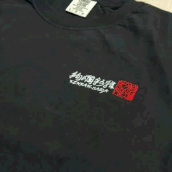 完成した「絢爛彩雅-KENRAN SAIGA-」のヘビーウェイトTシャツの胸元にある、ロゴ刺繍の仕上がりを見せる動画。和モダンなフォントの精緻な仕上がりと、刺繍糸の落ち着いた光沢感が伝わる出来栄え。