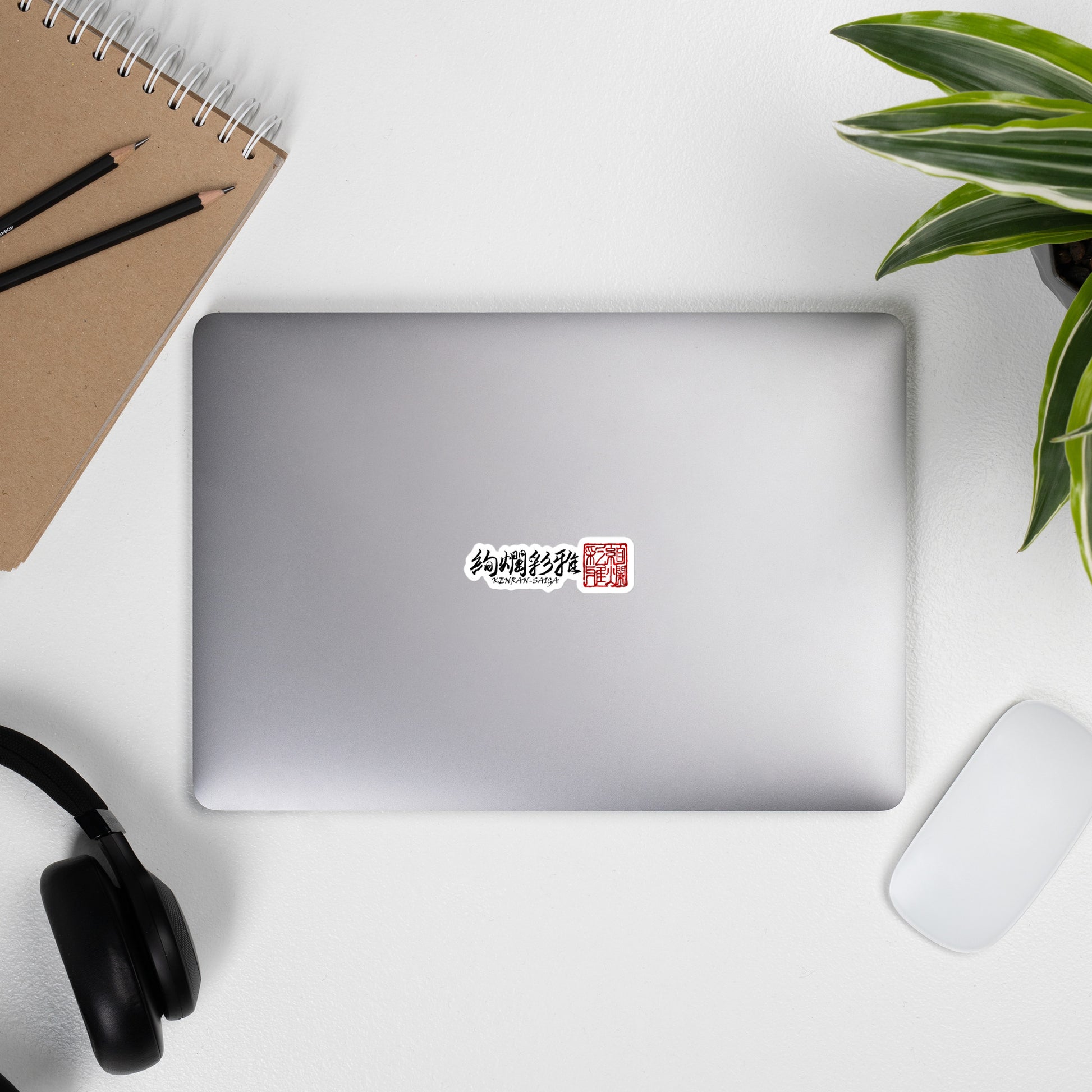 ノートPCに貼られた絢爛彩雅ロゴステッカーの貼付例。無機質なデバイスに洗練された和の美しさをプラスする、スタイリッシュな使用イメージ。